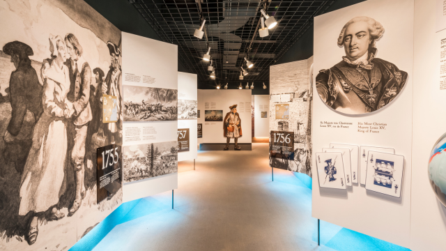 Two visitors are interacting with a costumed interpreter
