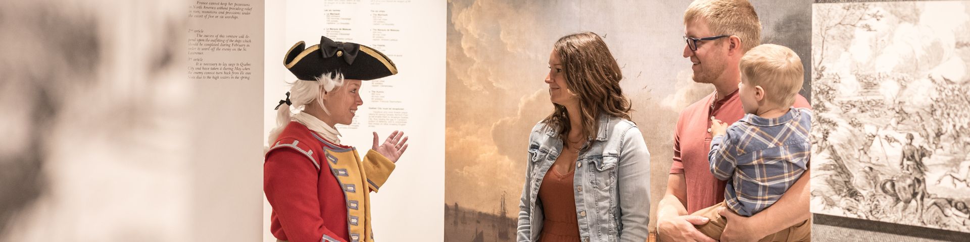 Une guide interprète personnifiant un militaire anglais parle à une famille dans une exposition. 