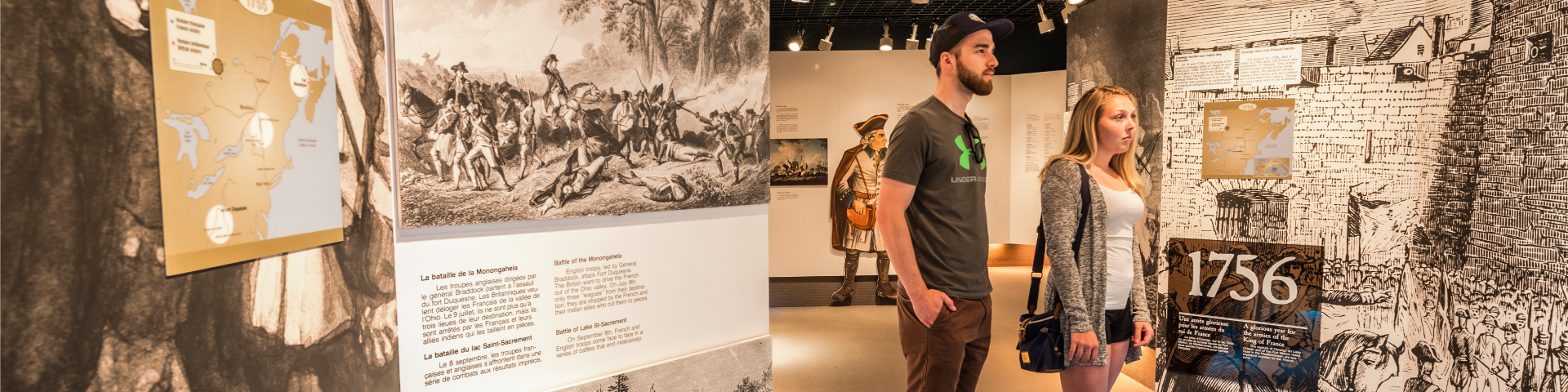 Deux personnes regardent un panneau d'interprétation dans une exposition muséale. 