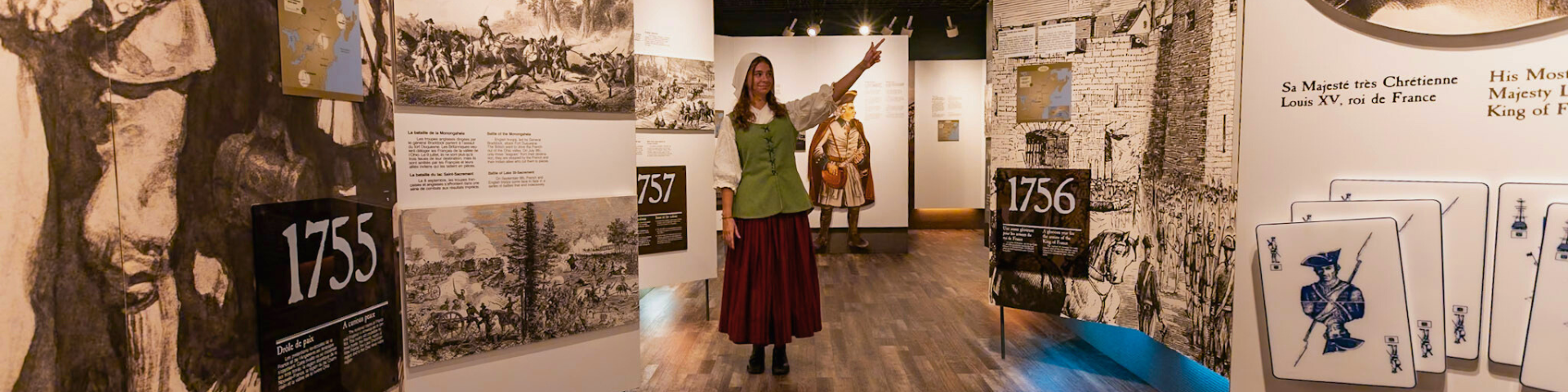 Une employée en costume d'époque pointe un panneau dans une exposition muséale. 