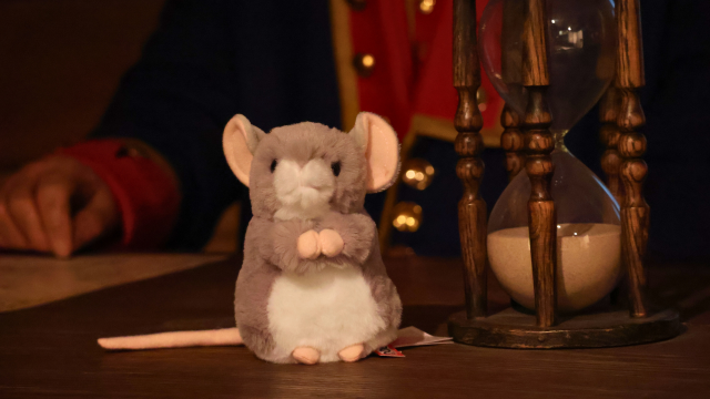 Stuffed mouse next to an antique hourglass.