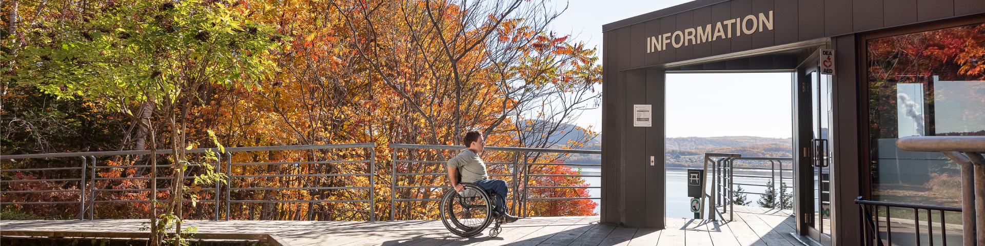 A wheelchair user on a boardwalk is about to enter a museum. 