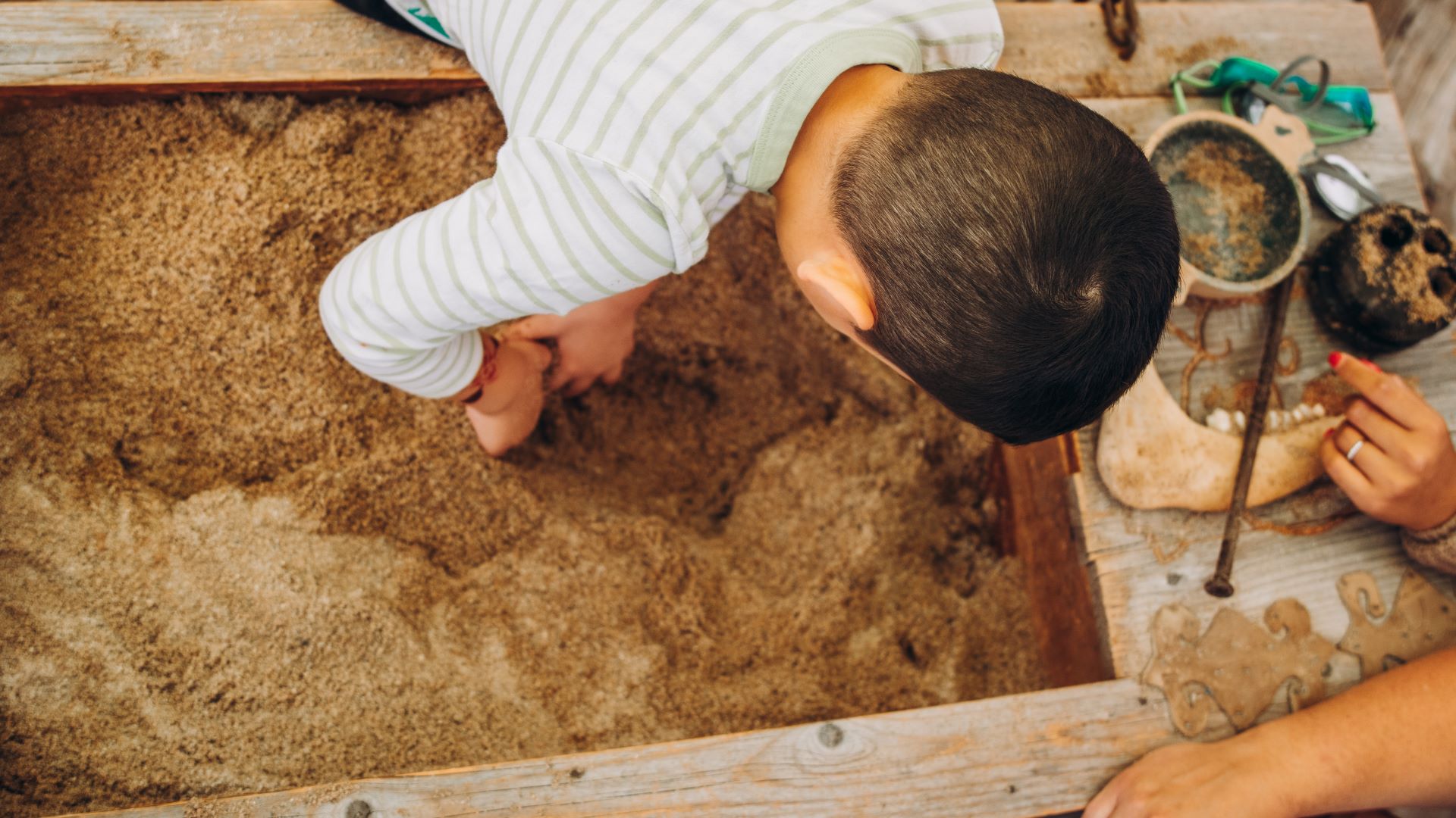 Un enfant creuse dans un carré de sable.