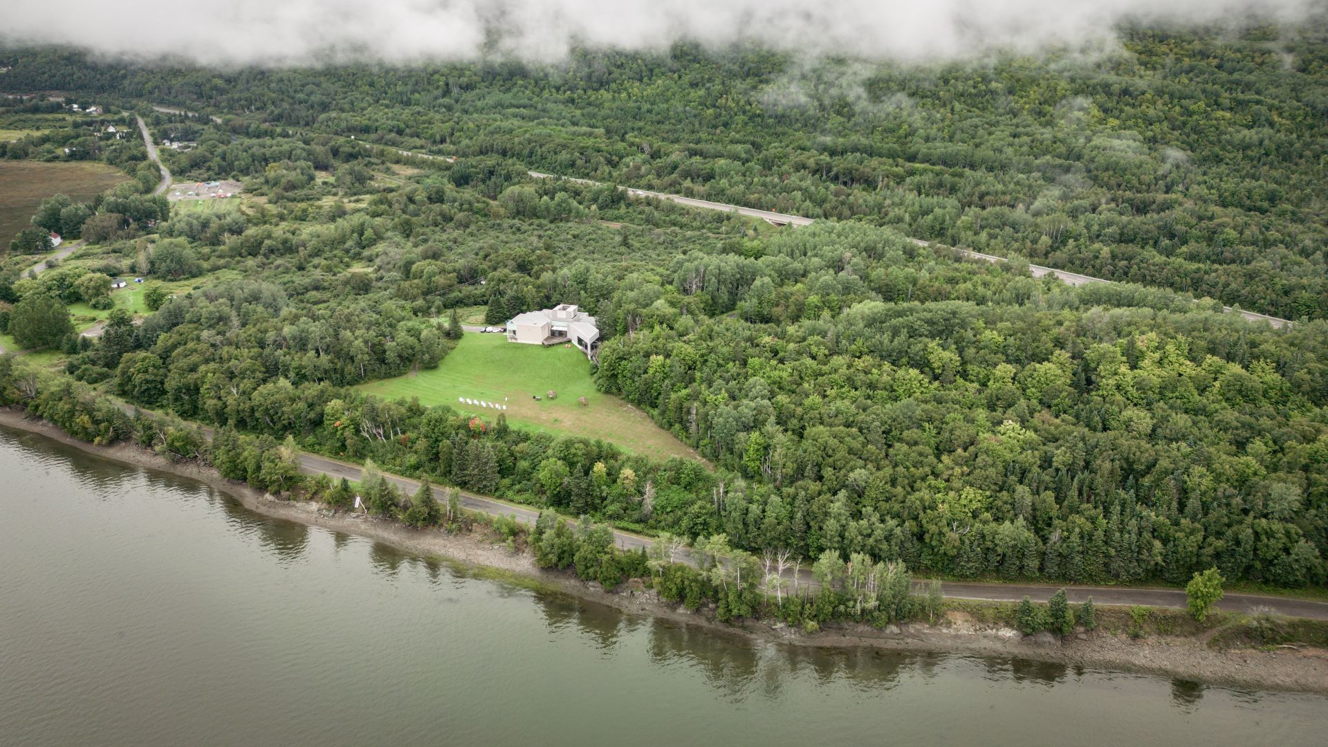 Aerial view of a building surrounded by trees next to a river.