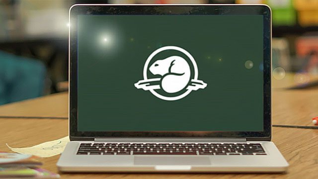 A laptop displaying the Parks Canada logo on its screen sits on a desk in a classroom.