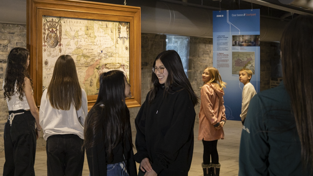 A group of high school-age students look at a historical map at the Saint-Louis Forts and Châteaux national historic site.