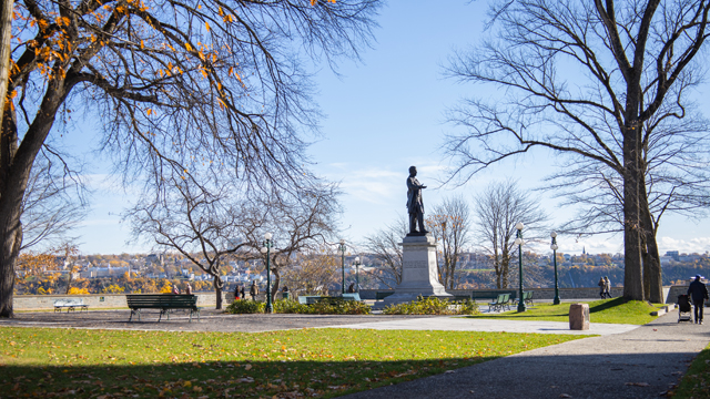 Vue du parc Montmorency avec la statue de Georges-Étienne Cartier au centre, des arbres mature et Lévis en arrière-plan.