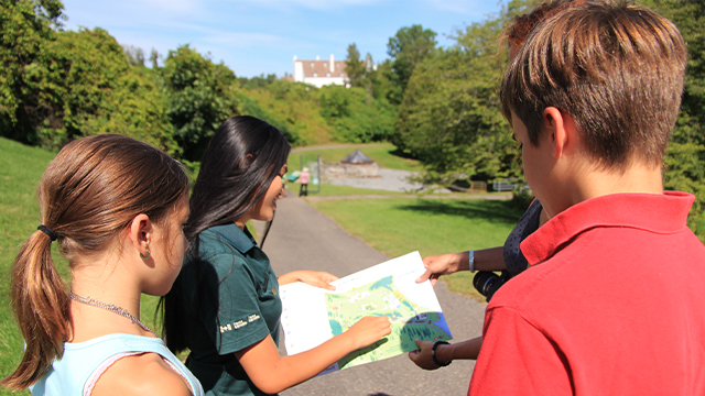 A Parks Canada guide in her twenties leads a guided tour of the archaeological remains at Forges du Saint-Maurice National Historic Site for two children and their mother.
