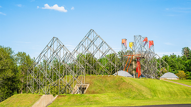 Metal structures expressing the exterior volumetry of the former Forges du Saint-Maurice National Historic Site buildings.