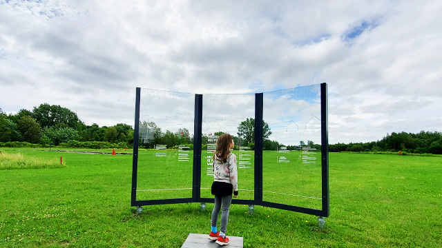 Young girl at the Forges du Saint-Maurice National Historic Site reading the interpretive panel presenting the village at Forges du Saint-Maurice.