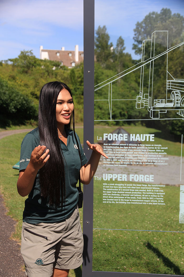 A female Parks Canada guide explains the history of the high forge at Forges du Saint-Maurice National Historic Site.