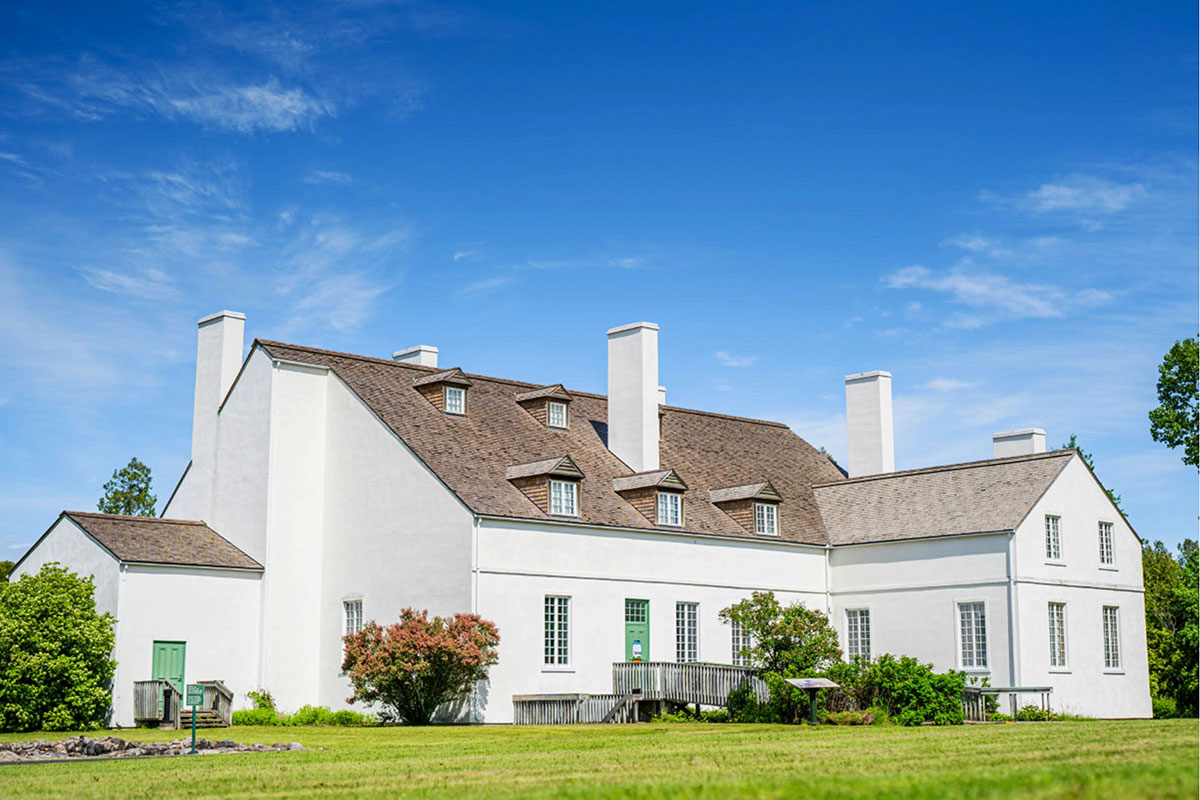La grande maison - a large white Québec ancestral house under a summer sky.