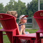 Famille assise sur les chaises Adirondack rouges de Parcs Canada