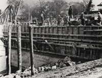 Thirteen workmen on the wood formwork that restrains concrete, during the construction of the present lock in the Saint-Ours canal in 1931.