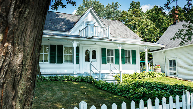 La maison familiale de Louis S. St-Laurent, qui fait partie des bâtiments à visiter au lieu historique national Louis-S.-St-Laurent, est illuminée sous le soleil estival et bordée de bosquets et de fleurs.
