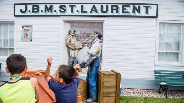 Deux jeunes garçons s’amusent avec des jeux antiques en plein été lors de la Foire d’antan du lieu historique national Louis-S.-St-Laurent.