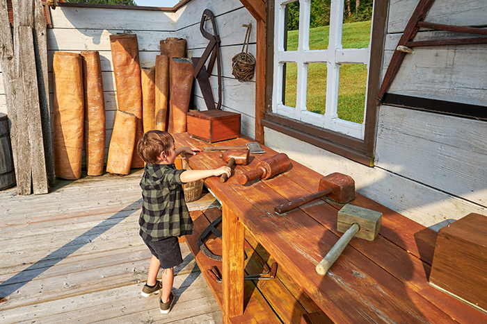 Un petit garçon découvre des outils d'époque en bois