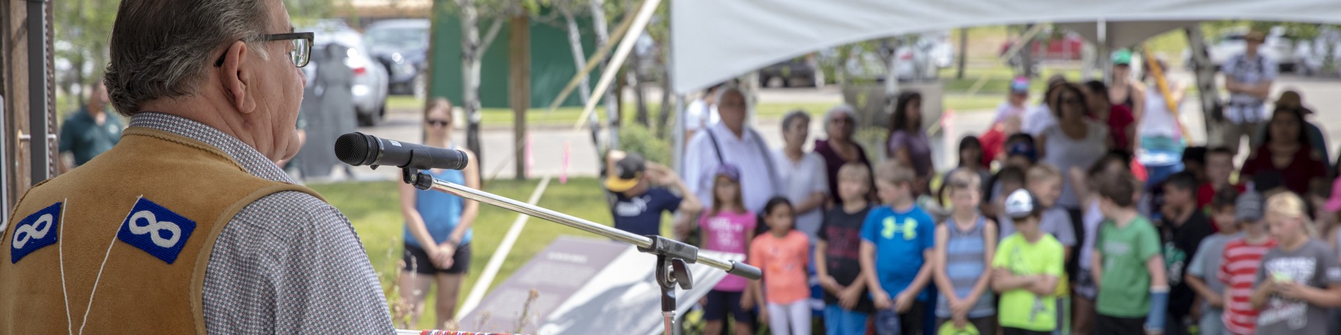 A man speaks to a group of school kids during an assembly at Batoche National Historic Site during National Indigenous People's Day.