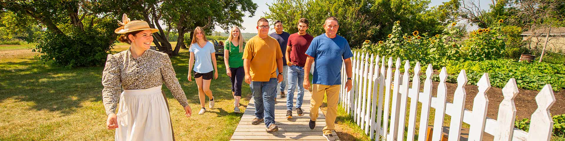 Une interprète de Parcs Canada en costume d’époque marche le long d’un groupe de visiteurs sur un trottoir.