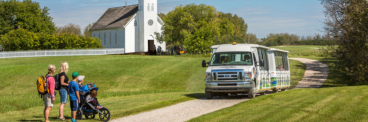 A shuttle picks up a family by the church. Batoche National Historic Site.
