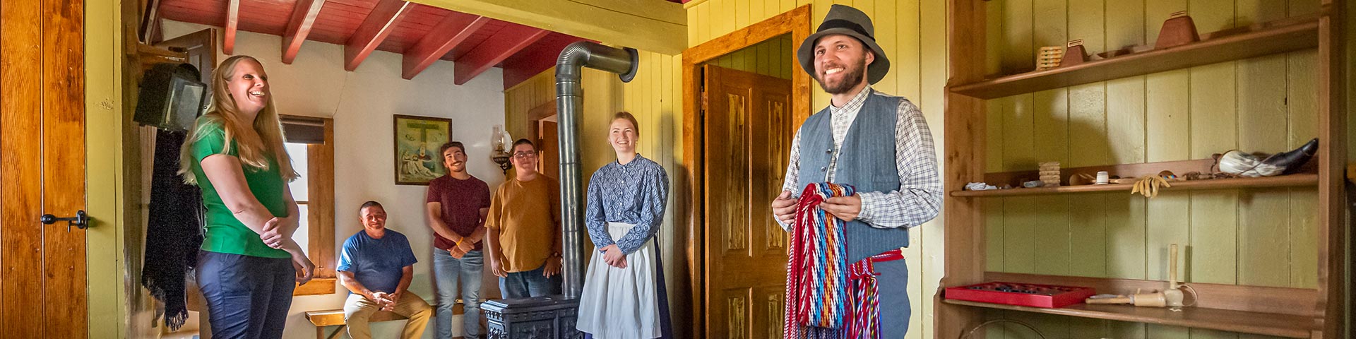 A Parks Canada interpreter shows off a Métis sash to a group of visitors.
