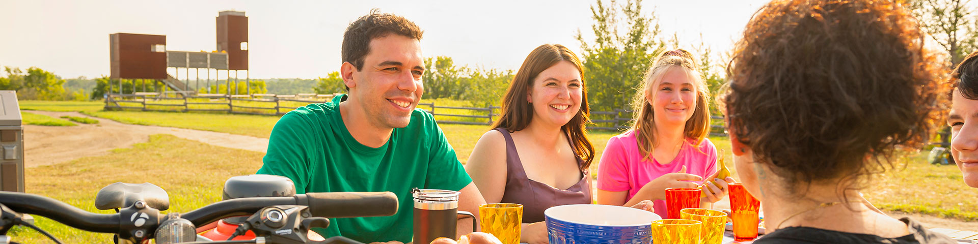 Three visitors smiling have a picnic at the East Village.