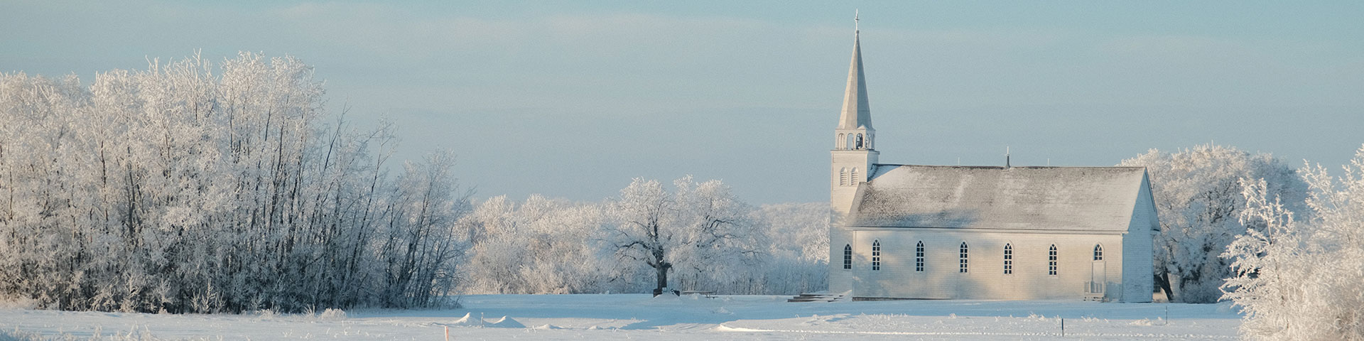 Église au lieu historique national de Batoche entourée d’arbres par une journée d’hiver.