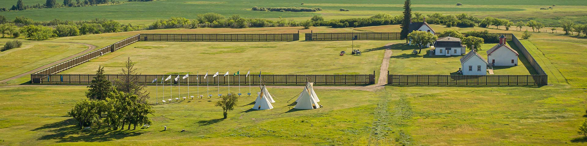 Aerial view of the fort and four tipis set up by the flag display on the grounds of Fort  Battleford National Historic Site. 