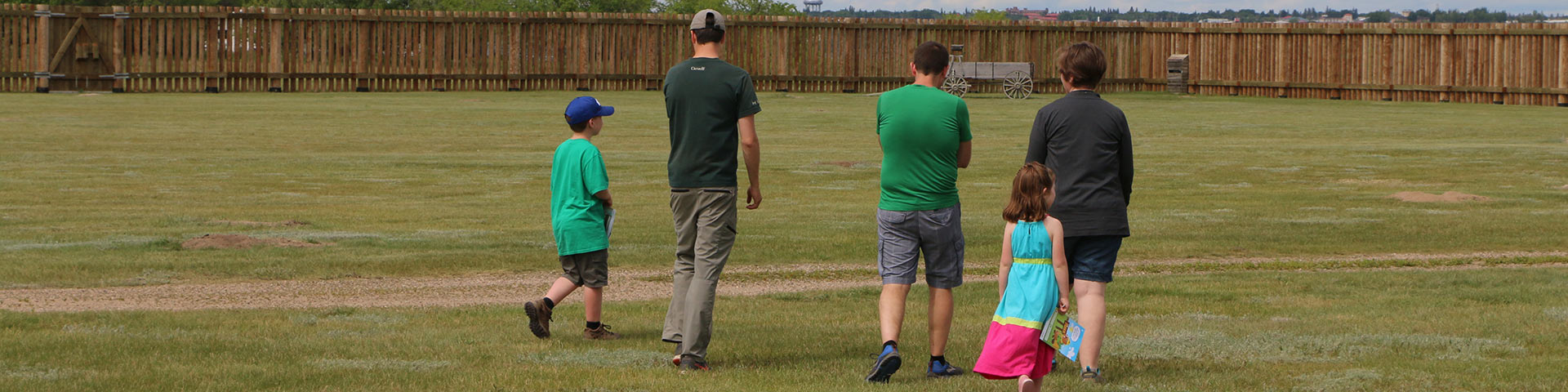 Parks Canada staff person and visitors walk across the grounds at Fort Battleford National Historic Site.