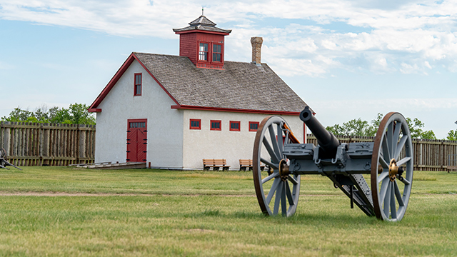 Sick Horse Stable at Fort Battleford with a field gun in the foreground. 