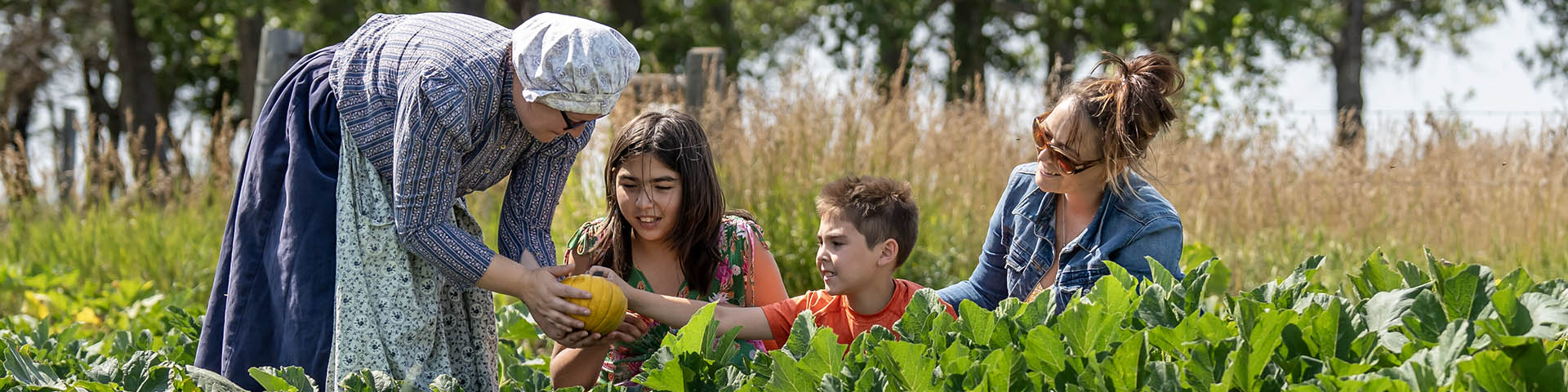 Famille de trois personnes dans le champ de citrouilles avec un interprète en tenue historique