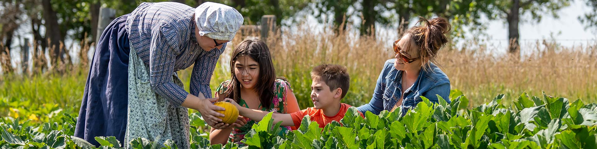 A family of three in the pumpkin patch with an interpreter in historical clothing. 