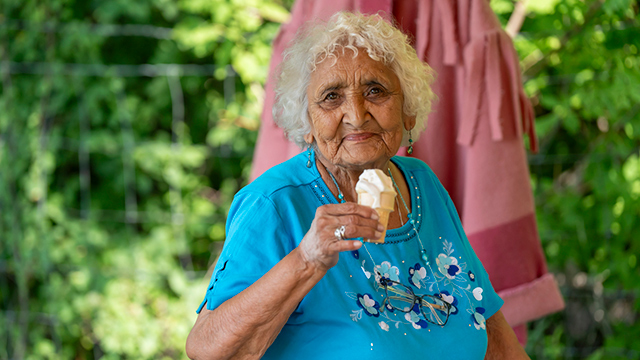 An elder holding an ice cream cone looking at the camera