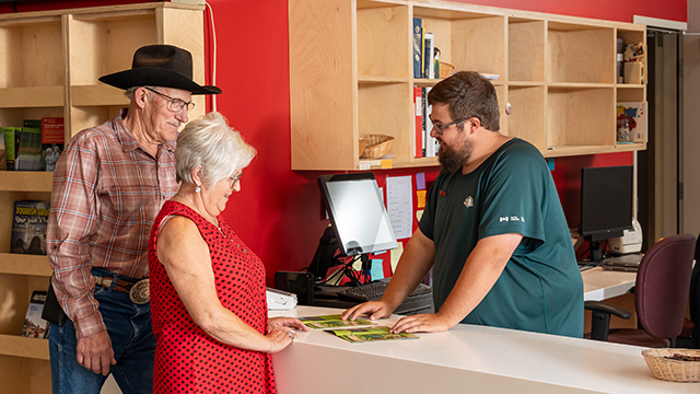 Un membre du personnel de Parcs Canada montre à deux visiteurs une carte du site.