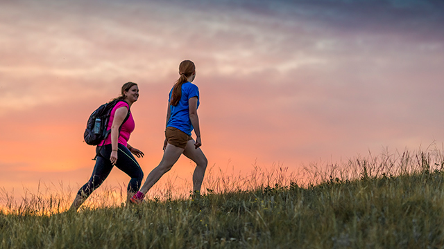 Two hikers walking in the Cypress Hills at Fort Walsh National Historic Site at dusk.