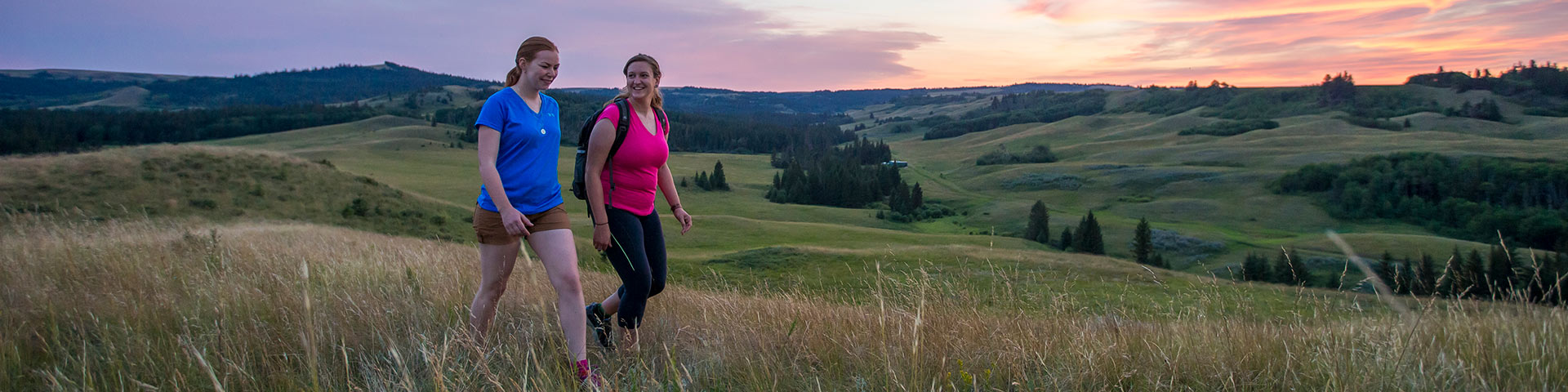 Two hikers walking in the Cypress Hills at Fort Walsh National Historic Site at dusk.