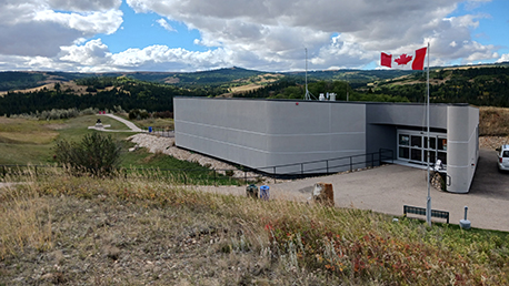 Un bâtiment avec des portes coulissantes en verre et un drapeau canadien flottant au-dessus