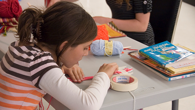 Youth learning the art of finger weaving. 