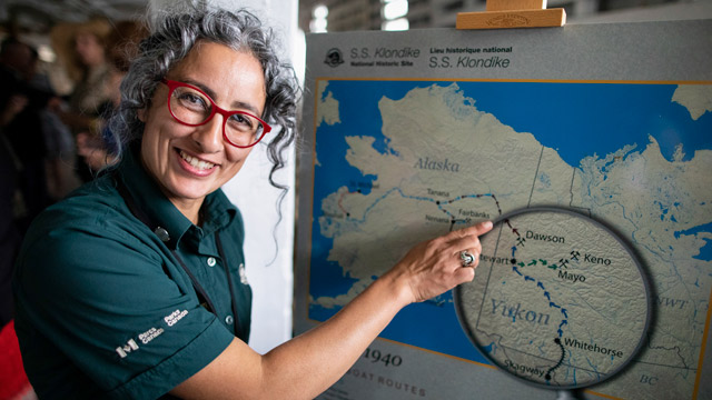 Souriant animatrice-guide du patrimoine de Parcs Canada montrant la carte des rivières Yukon