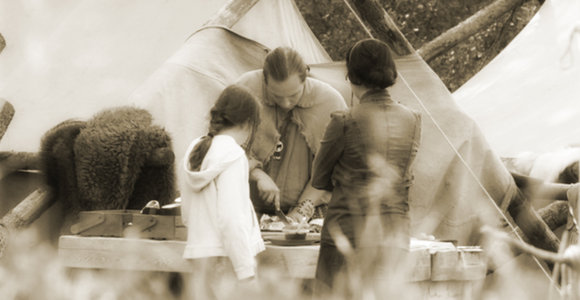 Métis interpreter preparing bannock for 2 children