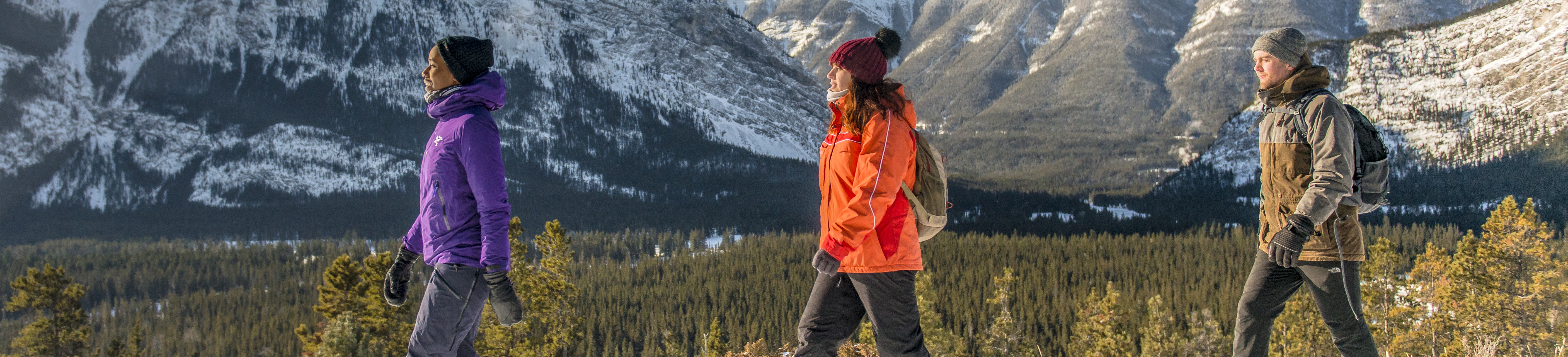 friends walk together in winter, mountains in background on a sunny day