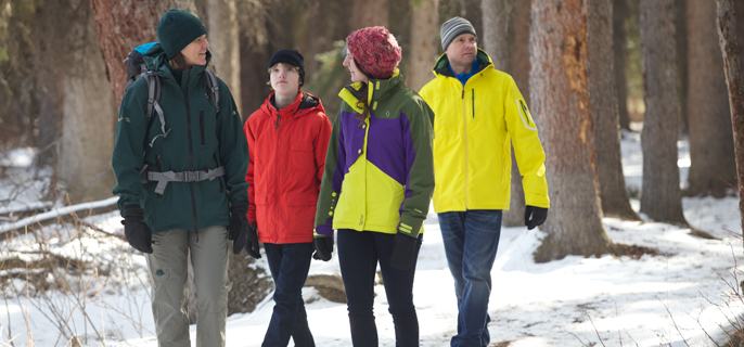 A Parks Canada interpreter talks with three visitors on a sunny winter day.  