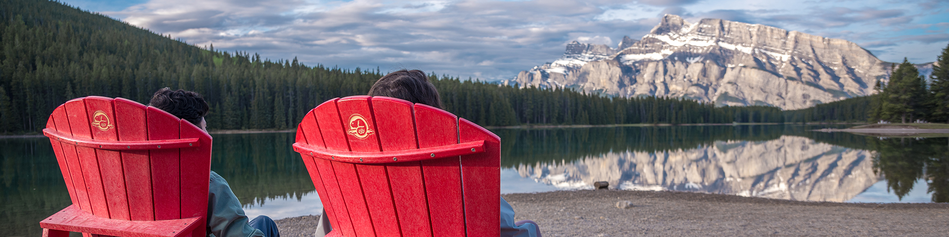 visitors sitting on red chairs in front of lake in banff 