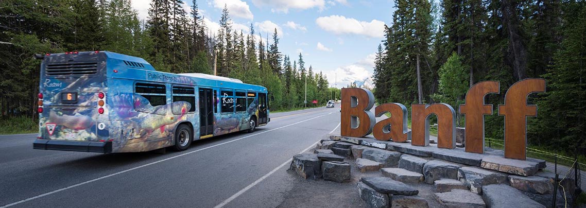 Roam transit bus driving past the Banff town sign