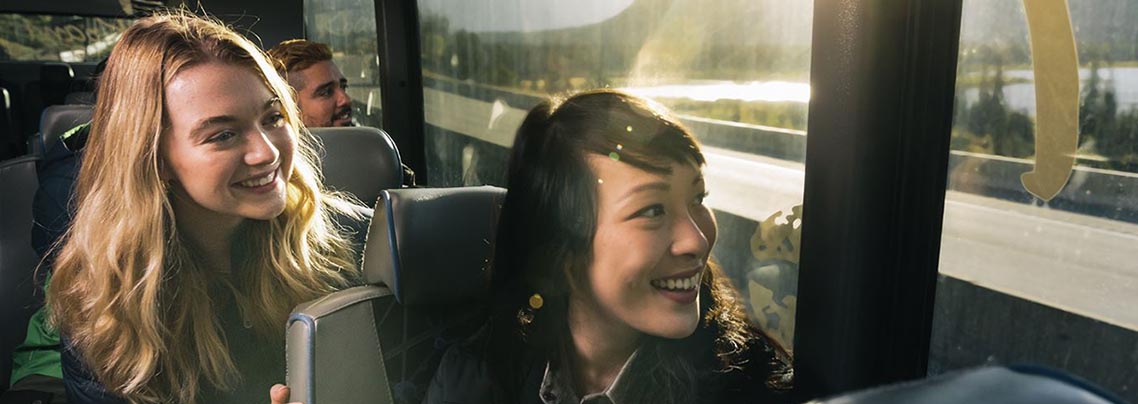 Passagers souriants dans un bus, avec coucher de soleil