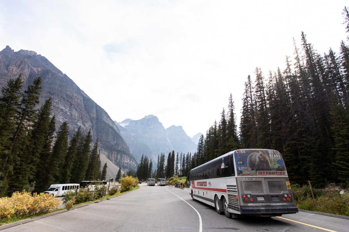 A bus pulls into a parking with mountains in the background. 
