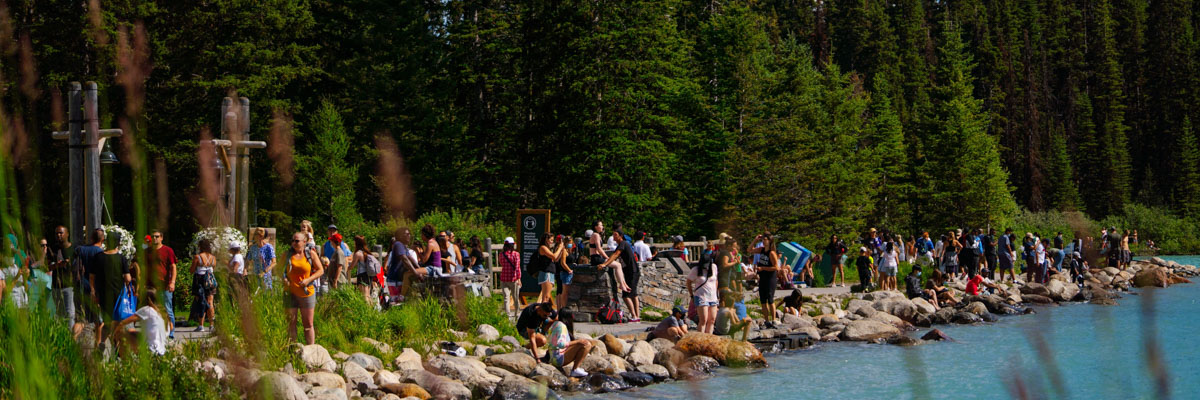 A large number of visitors crowd the edge of the Lake Louise lakeshore in the summer