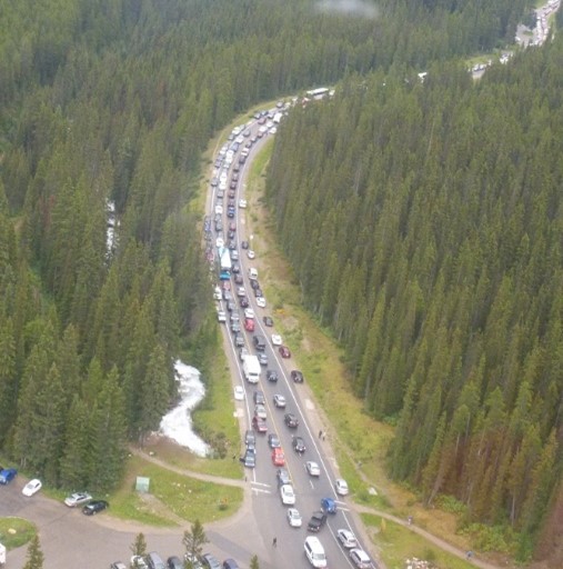 Aerial view of a two-lane road showing cars parked on both sides and gridlocked traffic in both lanes. 