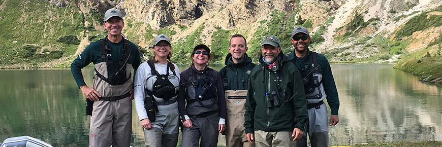 A team of six uniformed officers pose for a photo in front of hidden lake.