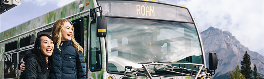 two young girls in front of a Roam transit bus